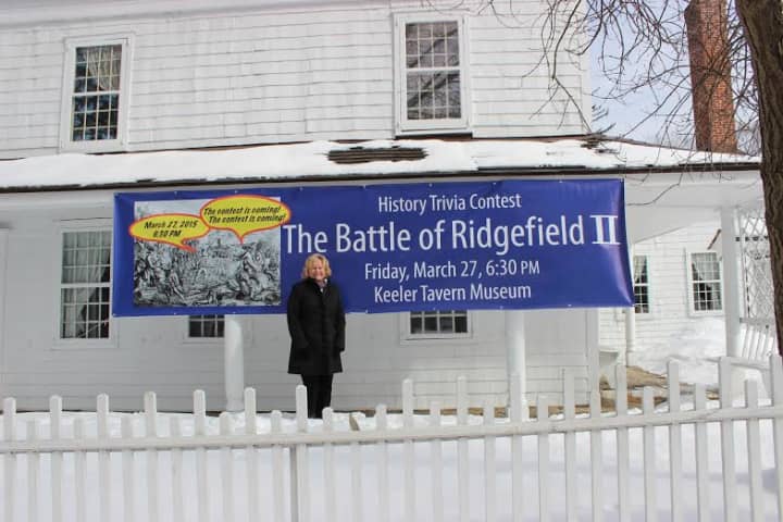 Hilary Micalizzi, Keeler Tavern Museum Program Chair, poses in front of History Trivia Contest banner.
