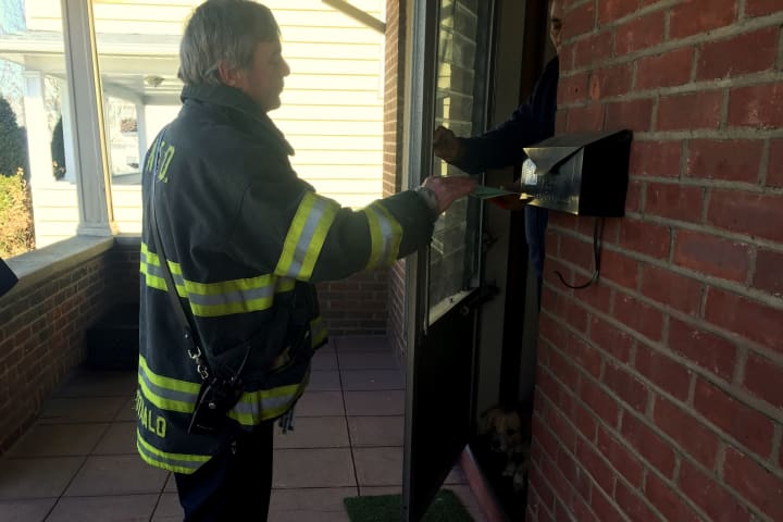Fire Inspector Kurt McDonald hands fire safety information to a resident following the fatal fire on Ely Avenue.