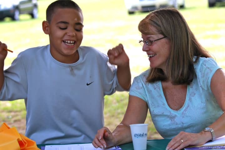 Cathy Osterhout, right, helps a student in a life skills class she teaches for Norwalk Grassroots Tennis.