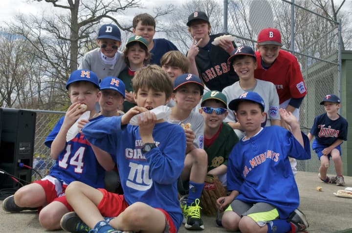 Players and families come out Sunday for Darien Little League&#x27;s opening day ceremonies. Here players pose on top of a dugout with hotdogs in hand. 