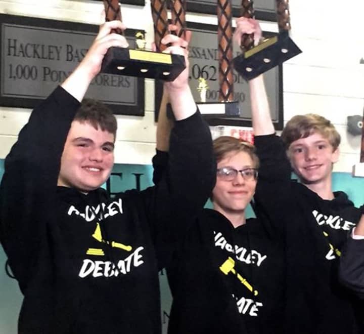 Hackley School&#x27;s debaters team raise their trophies.