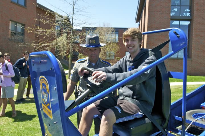 A student takes a ride on &quot;The Convincer,&quot; a 5 mph impact simulator, as Connecticut State Police Officer Chris Toney looks on, at the Thursday Safety Fair at Darien High School.