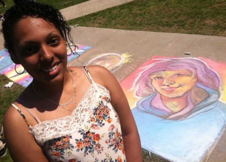 Sasha Cubero, 20, from Bridgeport, a Fine Arts student stands beside her portraiture at the Sidewalk Art Festival.