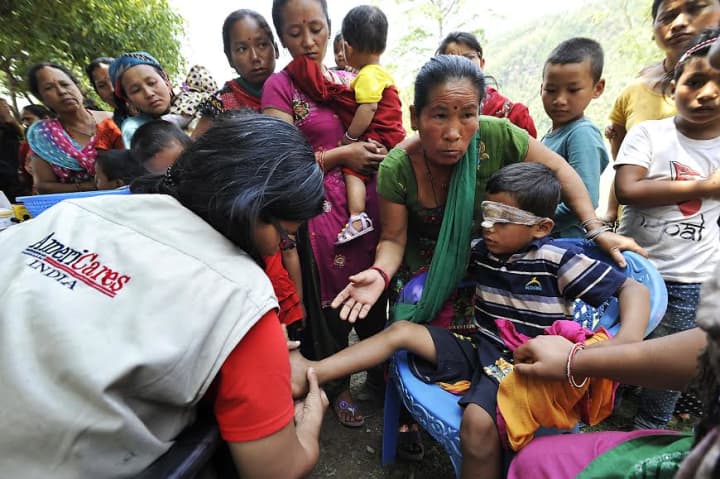 Dr. Swati Jha of AmeriCares treats a 7-year-old earthquake survivors infected wounds during a medical camp in Arughat, in Gorkha District.