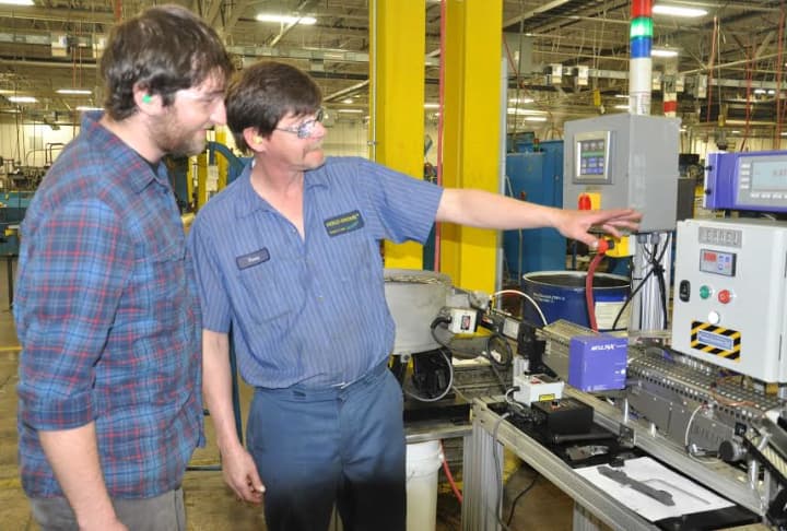 Tony Curtis of Bristol, right, a trainer at Wallingfords Holo-Krome, explains the operation of the laser-measuring machine to intern and Housatonic Community College manufacturing student Nicholas Thommen of Fairfield. 