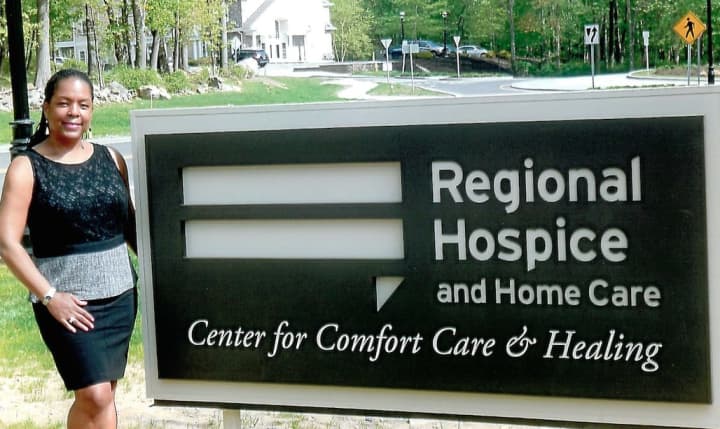 Valerie Cooper at the entrance sign to the Regional Hospice and Home Care Center for Comfort, Care and Healing in Norwalk.