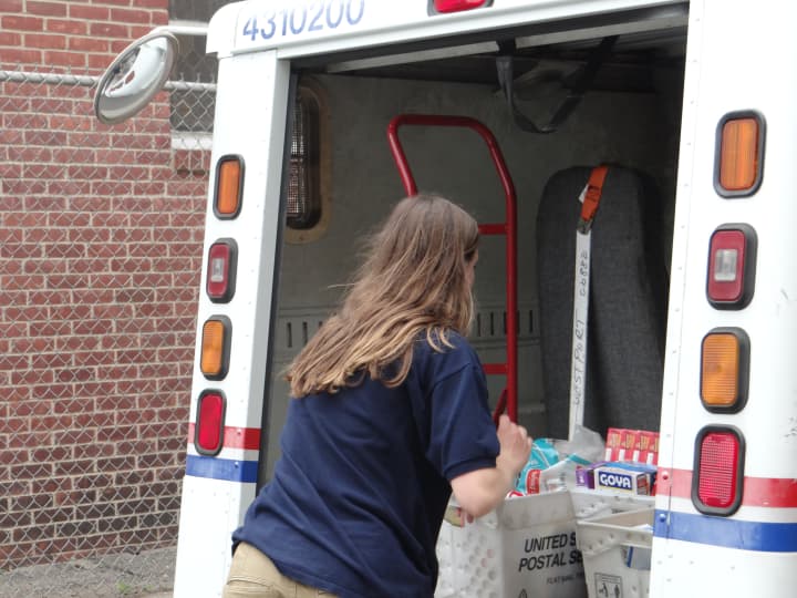 A Wilton High School student volunteer unloads a postal truck in Norwalk.