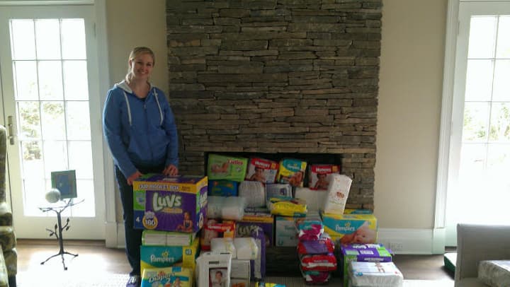 Junior League of Bronxvill chapter president Erica Sevilla with diapers and baby wipes collected in the drive.