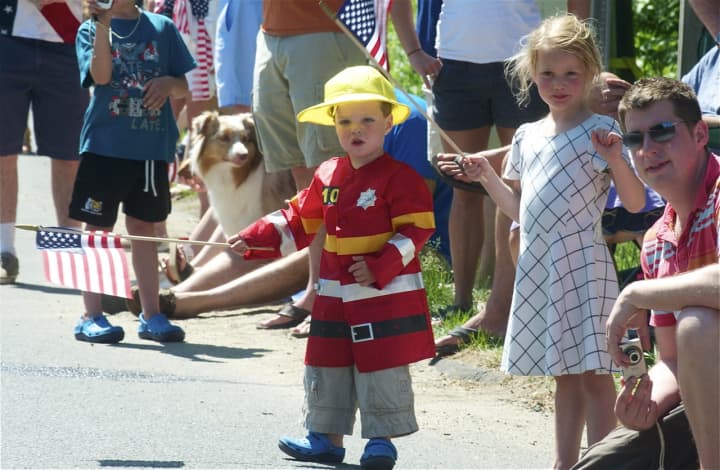 A young boy and a girl wave flags as they watch the parade Monday in Weston.