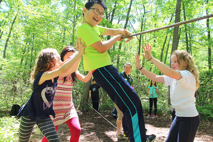 Columbus Elementary fourth grader Wilson Jiang navigates the low ropes course at the Taconic Outdoor Education Center with help from his classmates.