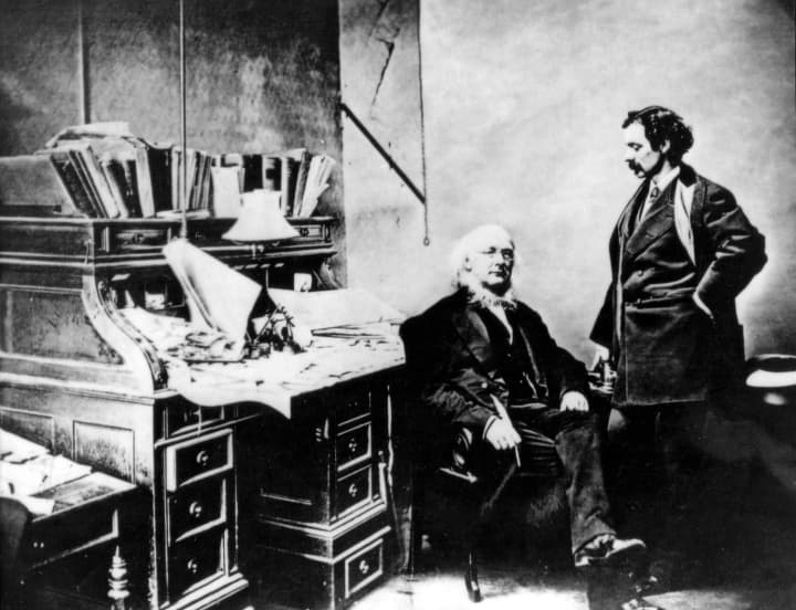 Horace Greeley seated at his desk in the New-York Tribune with publisher Whitelaw Reid.