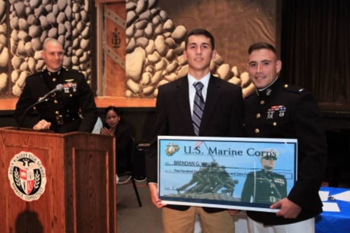 Maj. Thomas Abbott, left, and 1st Lt. Stefan Milan, right, present Brendan Walsh with a $180,000 scholarship during a high school awards ceremony June 3 at the Brien McMahon High School.
