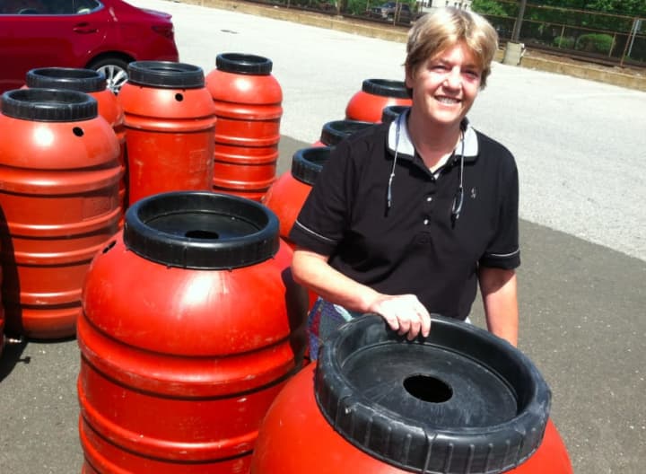 Cindy Muskus from Stamford standing beside a water barrel. She purchased her second one this year through SkyJuice, a New Hampshire company, and Aquarion.