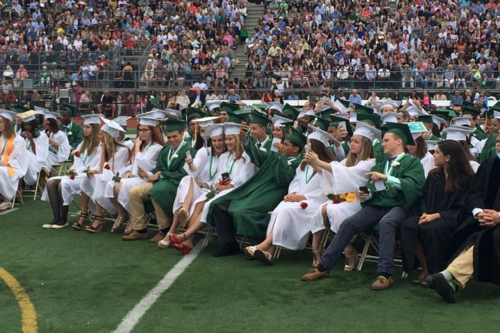 Graduating Norwalk High School seniors take selfies of themselves during the ceremony.