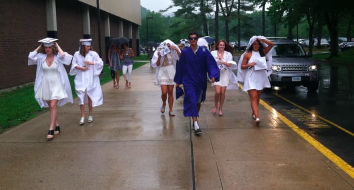 Graduates brave the rain as they walk to Wilton High School on Saturday.