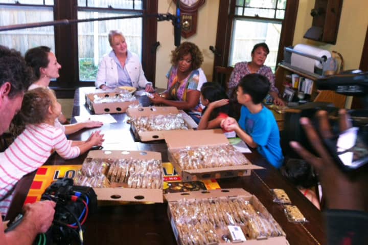 The Food Network&#x27;s Sunny Anderson, seated to right of head of table, helps pack granola bars at the Molina residence in Croton Falls.