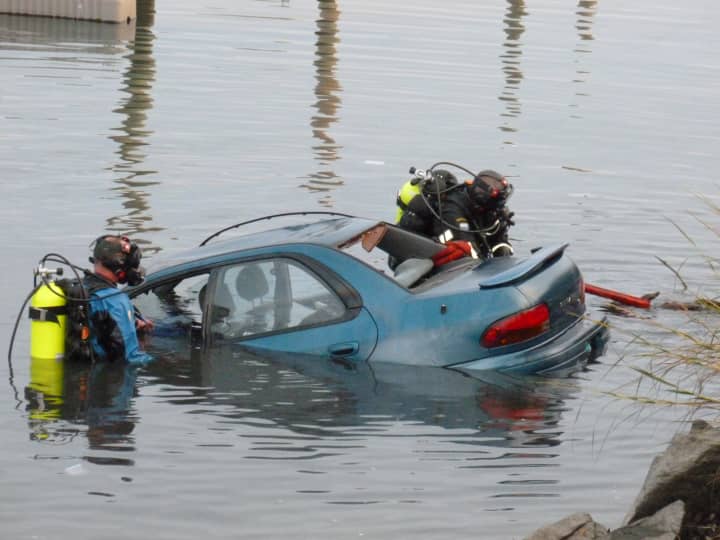 Norwalk police divers Greg Scully and Bruce Lovallo secure a car that was driven into the inlet at Veterans Memorial Park in Norwalk Saturday.