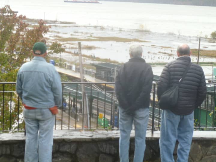 Hastings residents look over the Hudson River flood waters (foreground) that filled the riverfront adjacent to the Metro-North train station.