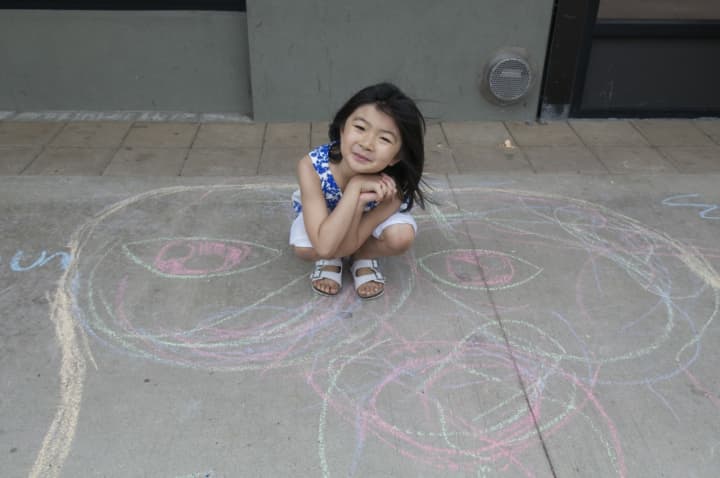 Suni, of Scarsdale, shows off her sidewalk chalk art at the Cross County Shopping Center.