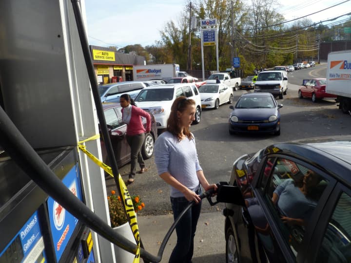 Katarina Kandracove fills up her car at a Mobil station on Yonkers Avenue Thursday as a line of cars waits behind her. 