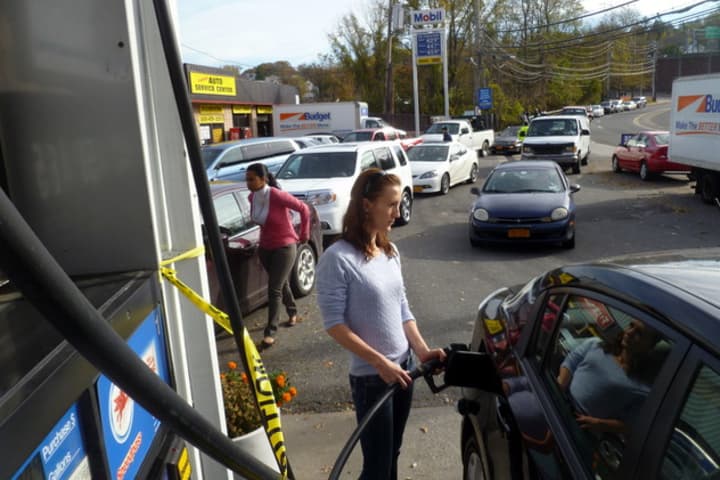 Katarina Kandracove fills her car at a Mobil station on Yonkers Avenue Thursday as a line of cars waits behind her. The city has announced it will now ration gas and limit customers to 10 gallons per visit.