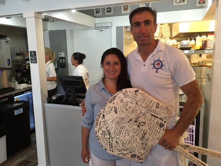 Sammy Palik and his wife pose with two paddles signed by their customers at their eatery Monday afternoon. 
