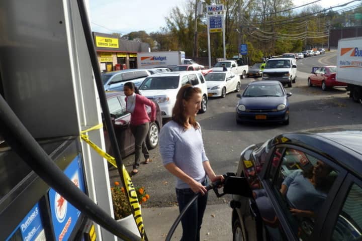 Katarina Kandracove fills her car at a Mobil station in Yonkers Thursday as a line of cars waits behind her.