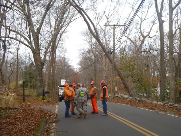 Connecticut National Guard members gather on Steep Hill Road in front of a tree they plan to cut down.