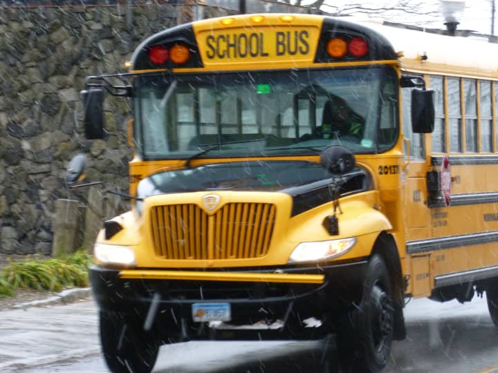 A Norwalk school bus drives down Water Street in the snow Wednesday to pick up students for an early dismissal. 
