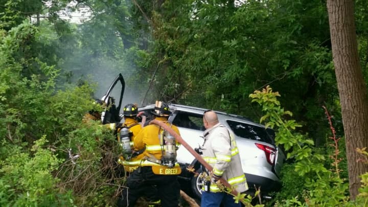 Firefighters doused flames coming from the engine of an SUV that crashed in Greenburgh along the Sprain Brook Parkway about 4:10 p.m. Thursday. A Westchester County police officer is credited with saving the driver&#x27;s life before the SUV caught fire.