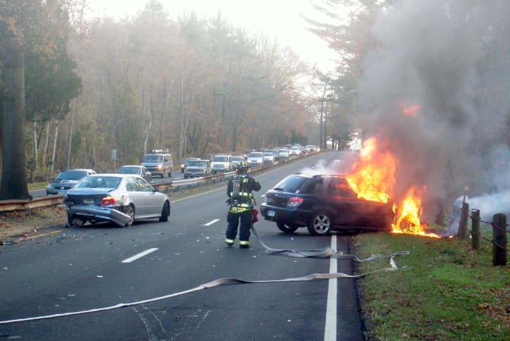 A Westport firefighter puts out flames in one of the two cars involved in an accident Wednesday morning on the Merritt Parkway. Both drivers said they hit a coyote that had wandered onto the road.