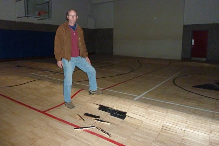 Scott Smith, communications director at the Westport Weston Family Y, stand in the Y&#x27;s Lower Gym, where flood waters caused the wood floor to buckle. 
