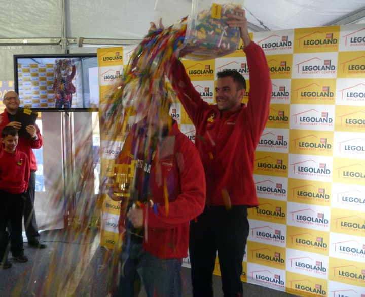 Jeremiah Boehr, Master Model Builder in Kansas City and judge of the Westchester competition, dumps a bucket of LEGOs on the head of Michael Tocidlowski after he was named master model builder of the Yonkers store Sunday at Ridge Hill. 