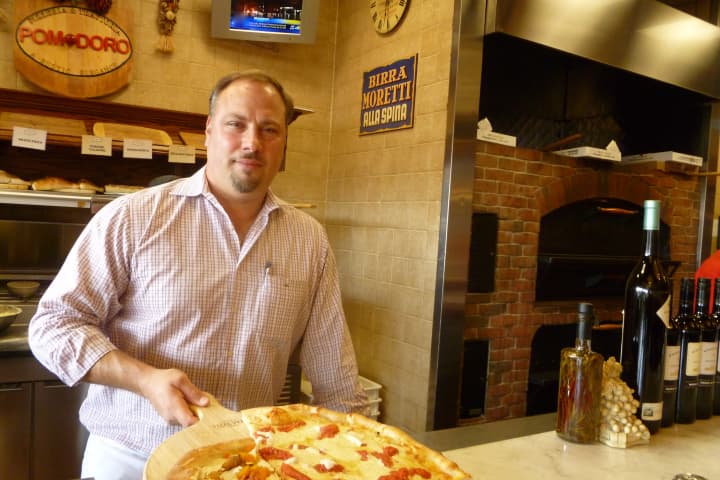 Mark Mazzotta, president and founder of Pomodoro Pizzeria and Trattoria in Greenwich, displays a pizza in his new wine and antipasto bar. 