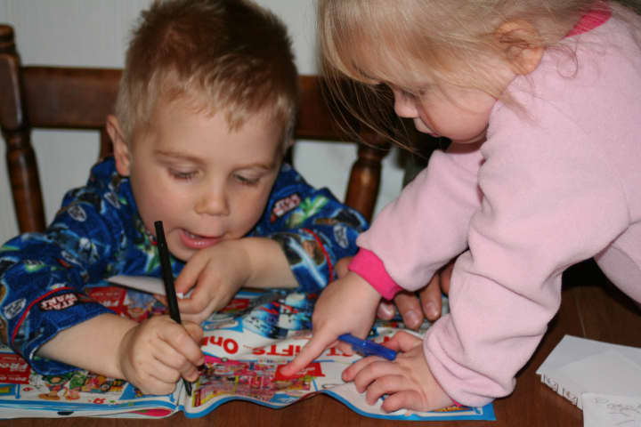 Maddy, right, helps her brother, Colin, select toys from a catalog to help him create his wish list for the Friends of Karen&#x27;s Adopt-a-Family program.