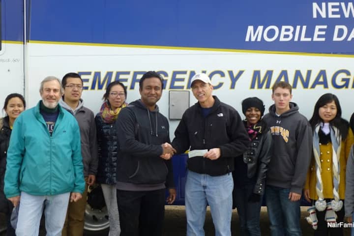 Rotary Club of Staten Island President Joe Marchese (sixth from left with ball cap) receives a donation from Westport Sunrise Rotary member Anil Nair (fifth from left), and club and student volunteers.