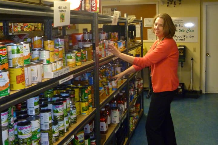 Nancy Coughlin, executive director of Neighbor to Neighbor, stocks the shelves of the organization&#x27;s food pantry. A $1.5 million gift from the Steven &amp; Alexandra Cohen Foundation will help pay for a new building for food and clothing operations.