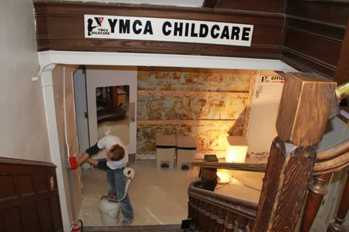 A worker repairs a flood-damaged wall in the Westport Weston Family Ys Child Care Center on Thursday.