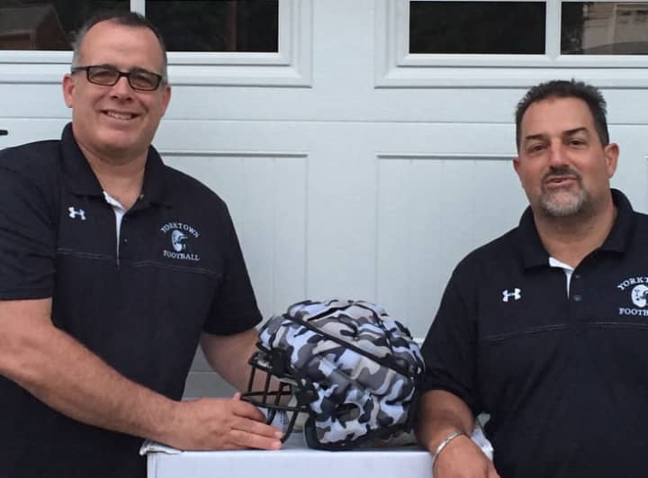 Yorktown Athletic Club football Commissioners Matt Talbert, left, and Joe DiCanio show one of the 160 Guardian soft-shell helmet covers the youth sports organization has purchased to help protect its athletes from head and body injuries.