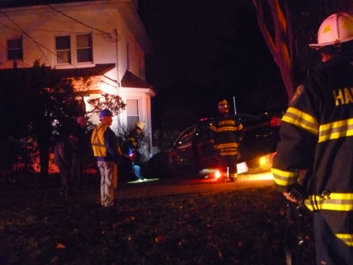 Firefighters watch a state police car being pulled from a house in Hawthorne on Saturday night.