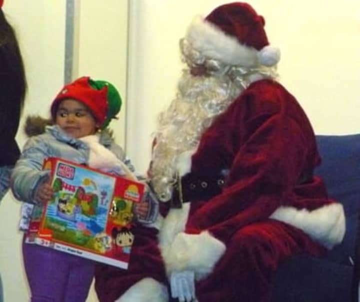 Santa giving a young Port Chester girl a present at last year&#x27;s holiday kickoff event. 