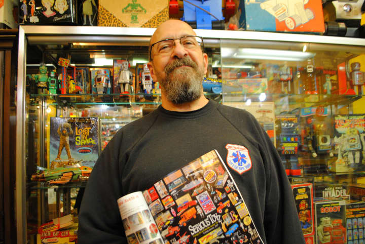 Serious Toyz owner Tom Miano, stands with an ad in &quot;Antique Toy World&quot; magazine. The store will be on the cover of the industry publication in January.