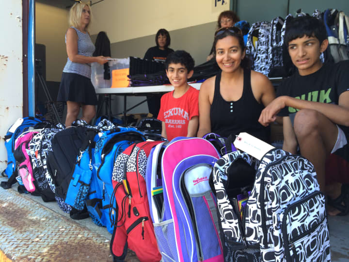 Priya Tambe, center, with sons, Sam, left, and Neil look over backpacks and school supplies at an Operation Backpack distribution site in Port Chester last year.