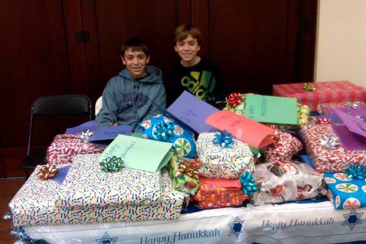 Chad, left, and Jonah Schwam pose with wrapped presents for children at the Pleasantville Cottage School. 
