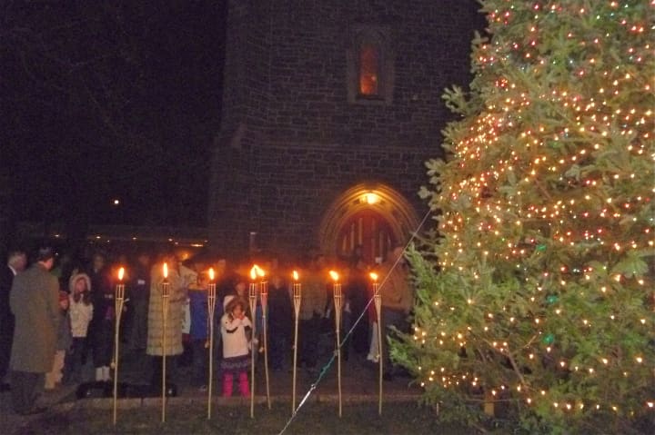 Greenwich residents gather at Christ Church in front of a Christmas tree and torches commemorating the start of Hanukkah.