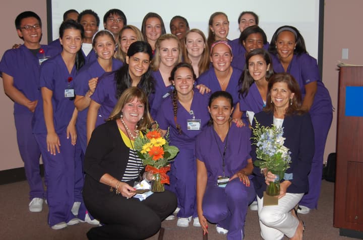 Annie Norris, nurse apprentice program counselor (front row, right), and Monica Purdy, nursing liaison for students (front row, left), congratulate the 22 graduates of White Plains Hospitals Nurse Apprentice Program.