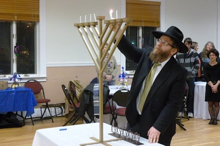 Rabbi Velvl Butman lights the menorah candles at Elmsford&#x27;s annual Hannukah celebration ceremony Thursday night.
