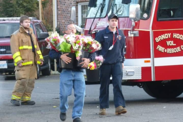 A man carries flowers at the Newtown firehouse next to Sandy Hook School in Newtown. 