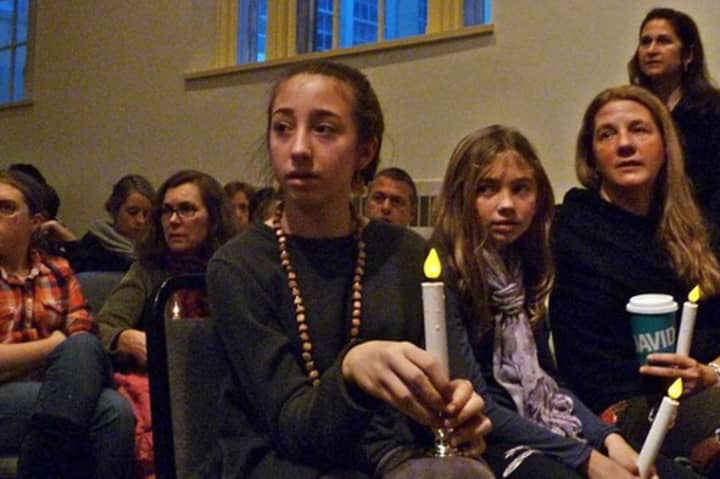 Lulu Busk, 13, her sister Bella, 10 and their mother, Andrea, sit with candles at the Westport memorial service Sunday evening to remember the victims of the Sandy Hook Elementary School shooting.