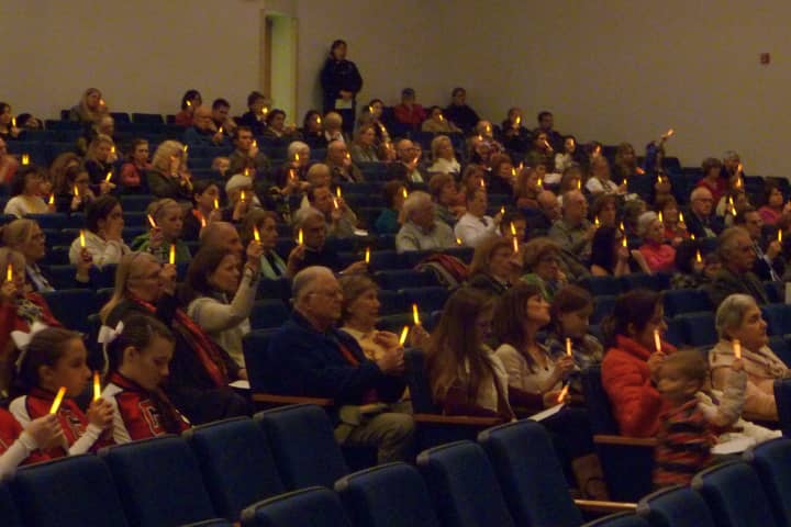 Attendees of the Greenwich Community Vigil in memory of the Newtown shooting victims hold up orange glow sticks while the names of the victims are read.